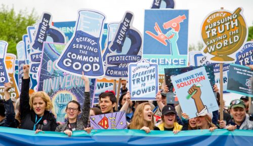 A graphic of the science community during an event displaying signs and posters.