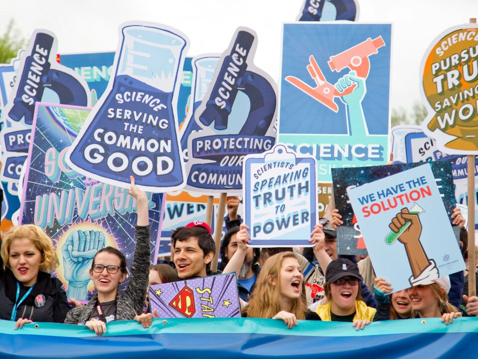A graphic of the science community during an event displaying signs and posters.